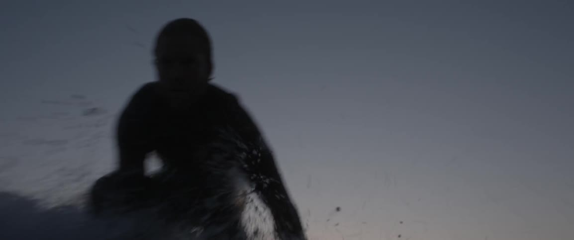 A man is riding the waves on his surfboard at dawn