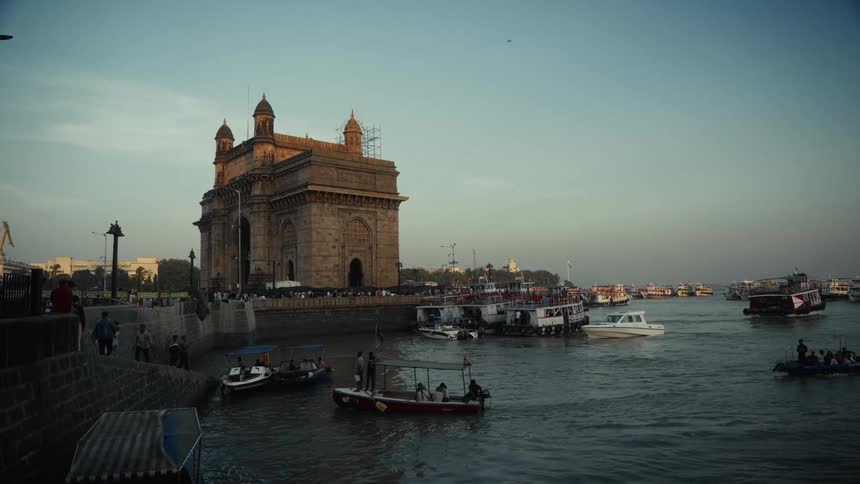 The gateway of india in mumbai over the water with many boats and passengers