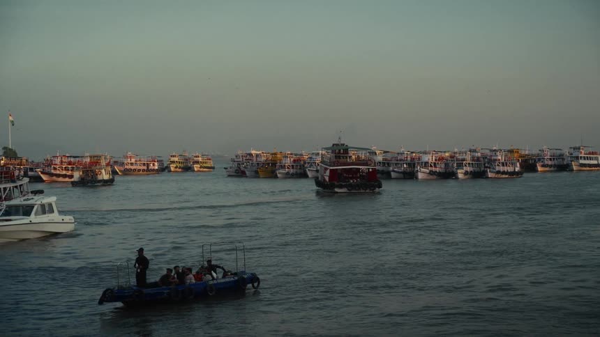 Inflatable boat with people moves past harbor crowded with colorful vessels under clear sky
