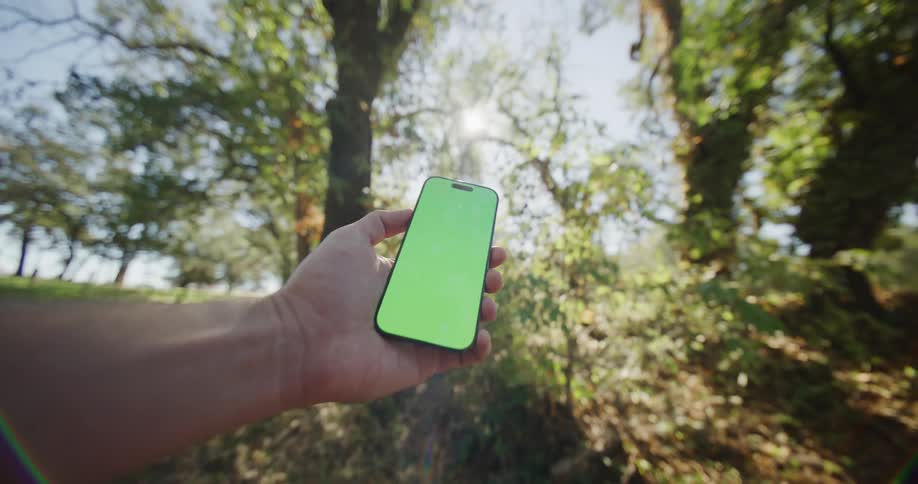 Man holds a mobile phone with a glowing green screen