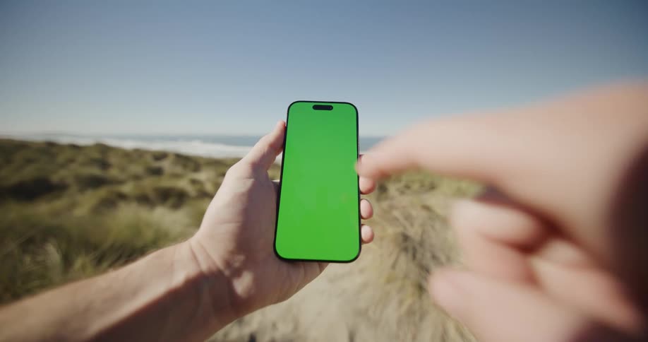 Hand points phone in sunny coastal setting