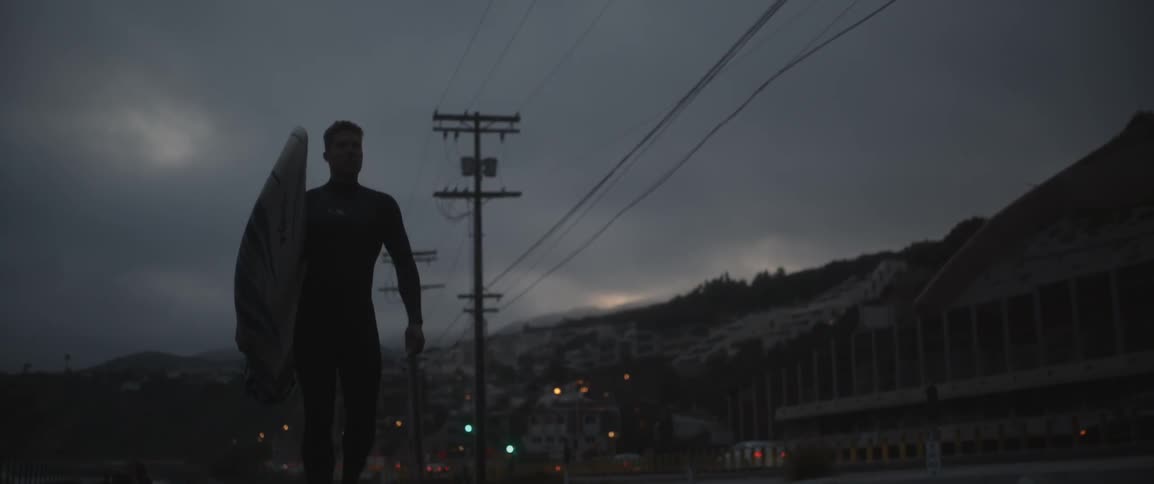 A man walks on the street with a surfboard
