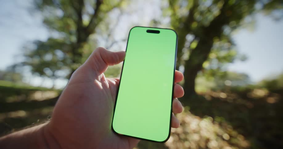 Man holds a mobile phone in his hand with a glowing green screen