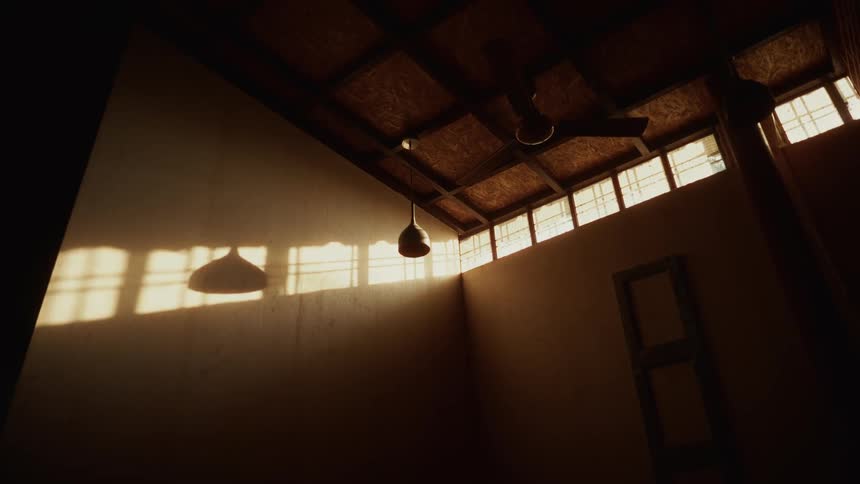 Sunlight streams through high windows casting bold shadows across wooden wall and ceiling