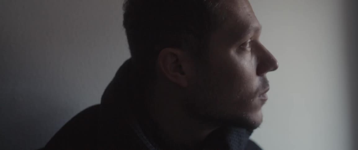A man leans forward in a dark area