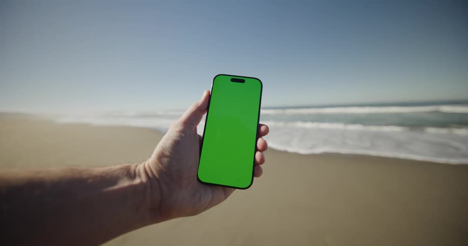 A person holding a smart phone outdoors on the beach