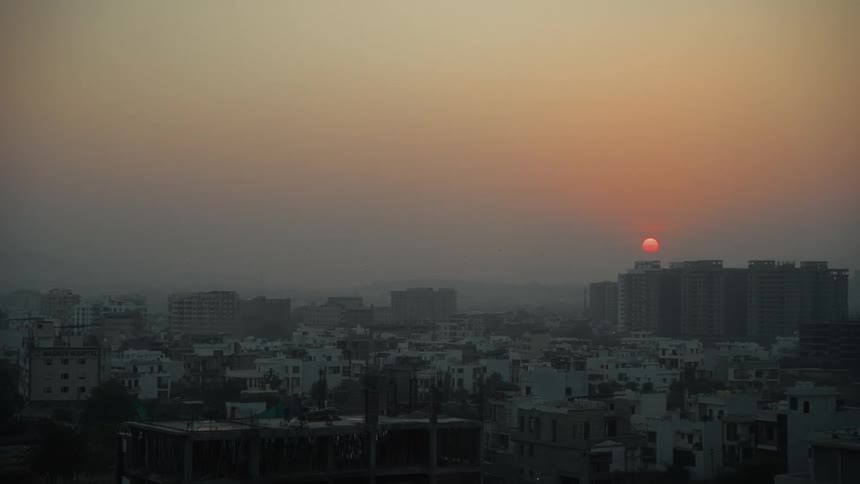 A city skyline glows at sunset filled with towering highrises and residential condos stretching across the horizon