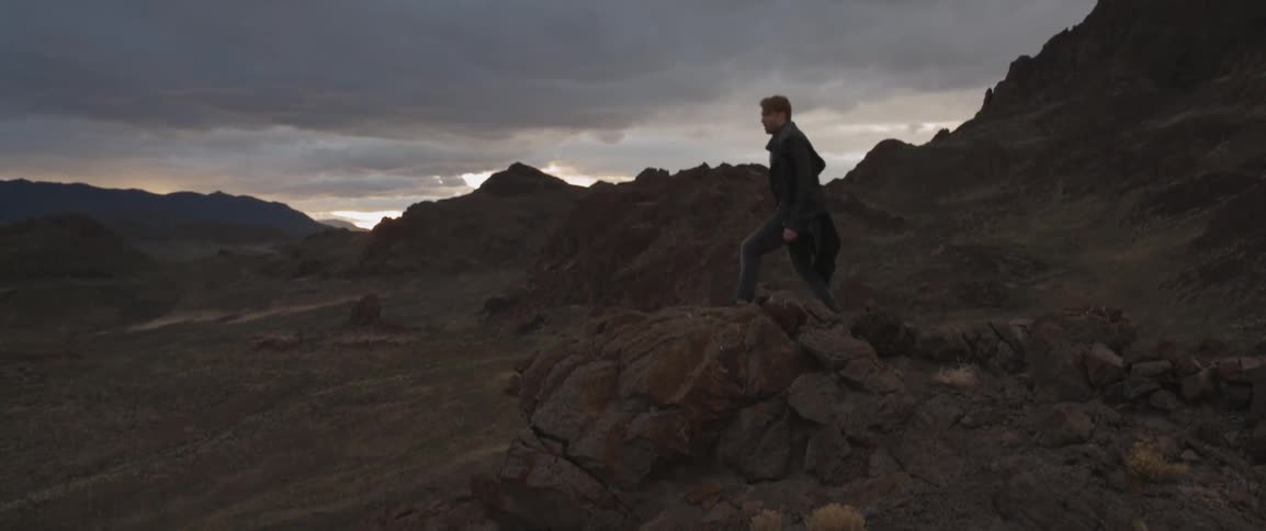 A man walks over rocks at dawn