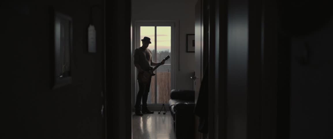 A man plays guitar near a tall window