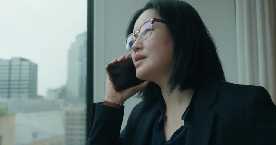 A woman talks on a cell phone next to the window in an office building