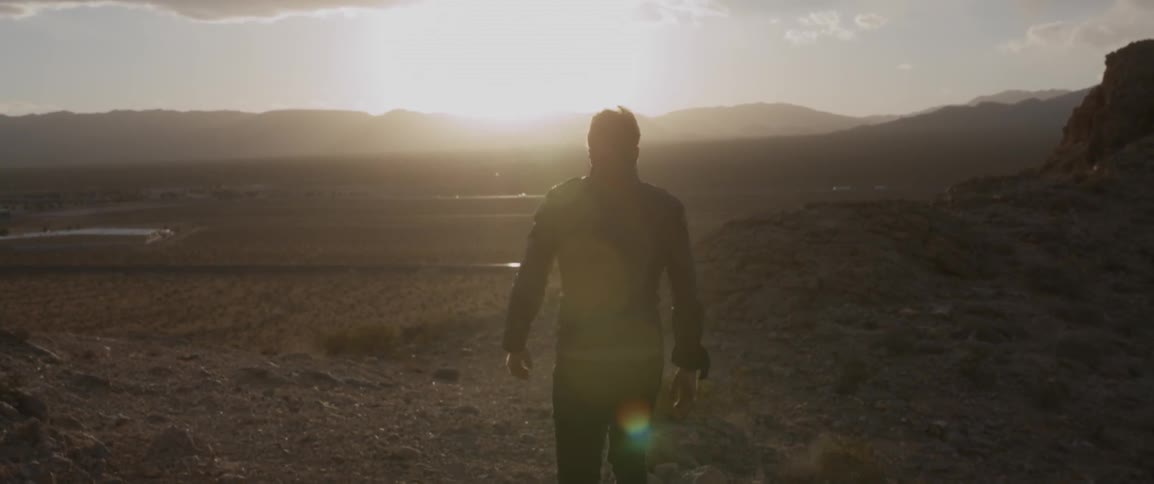 A man is walking down a slope in a desert setting during the day