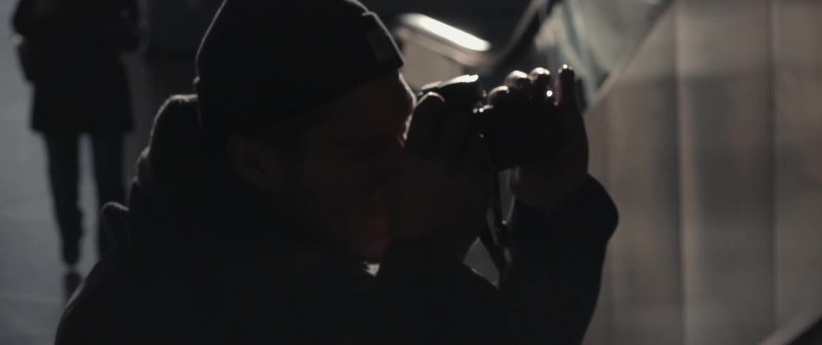 A man looks up and takes a photo of an escalator