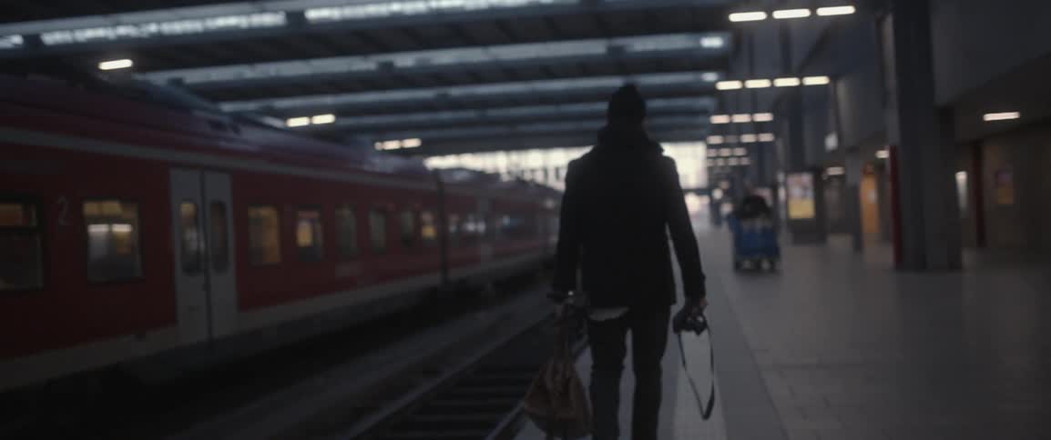 A man walks in a train station with a camera in hand