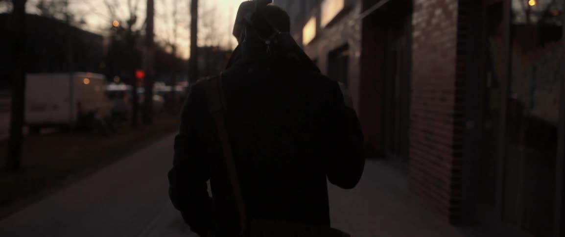 A man carrying a tripod walks down the street