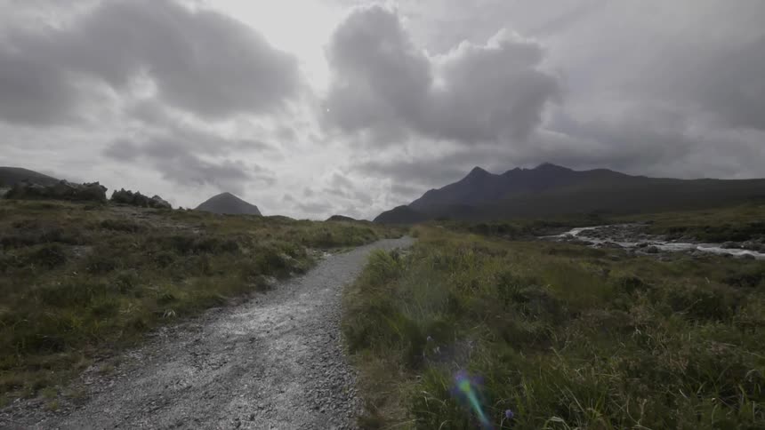 An empty road and field below a gray covered sky