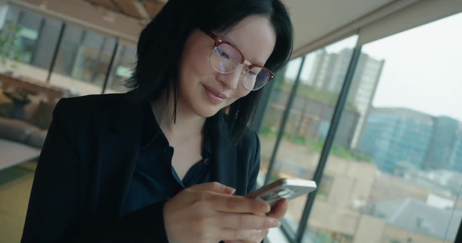 Businessperson checks phone in modern office with urban view and relaxed atmosphere