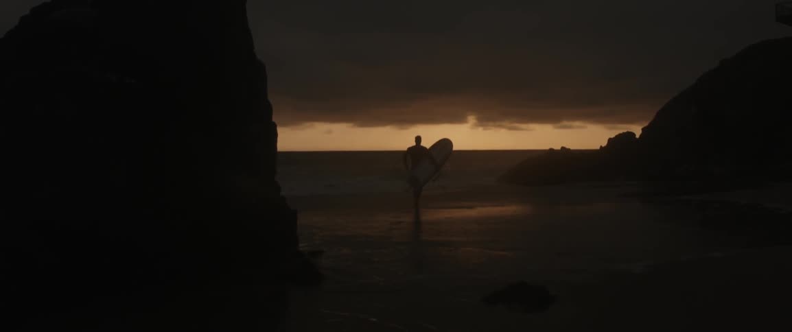 A man carries a surfboard running towards the water