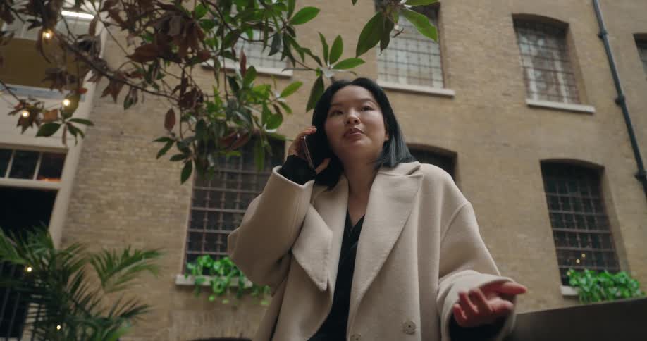 A woman is standing outside a building talking on her phone