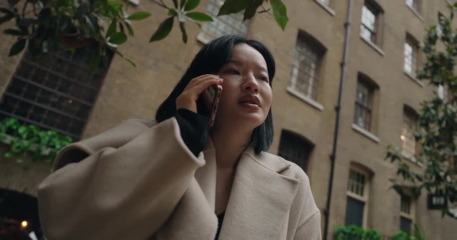 The woman talks on her phone and nods her head