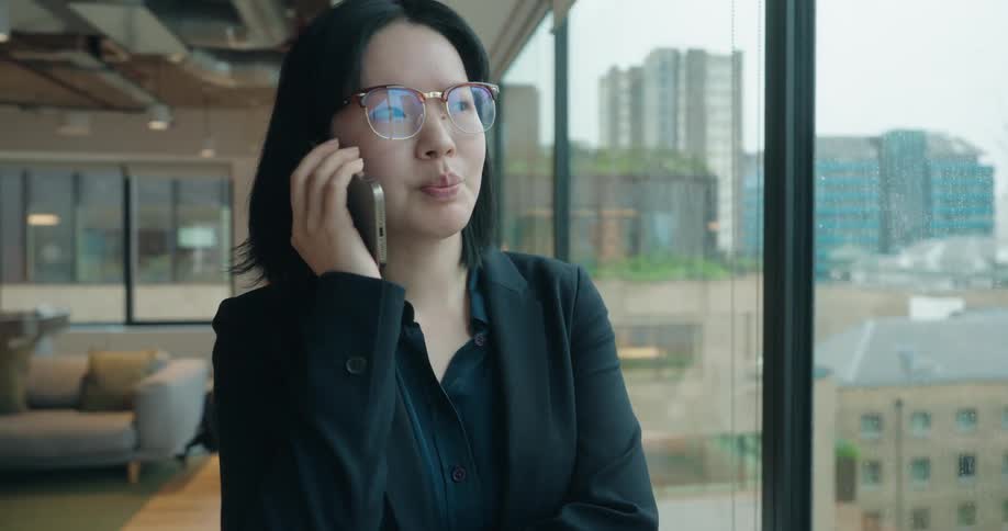 Professional talks on the phone while looking out at the city through the window