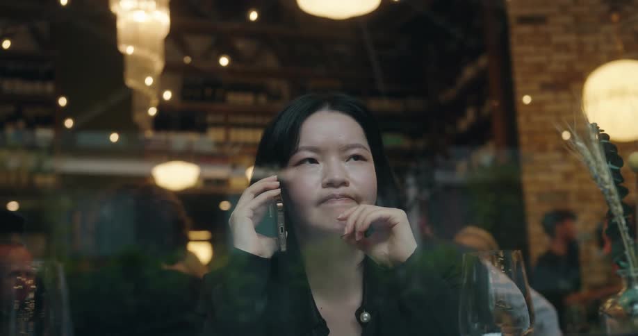 Woman talking on the phone inside a busy restaurant
