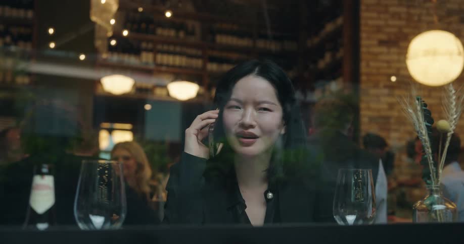 Woman on the phone inside a restaurant seen through the window