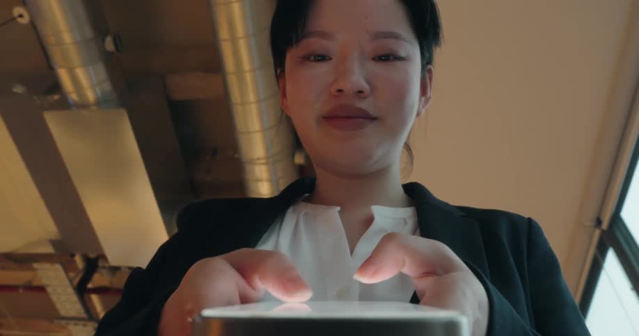 An asian woman quickly types a message on her smart phone