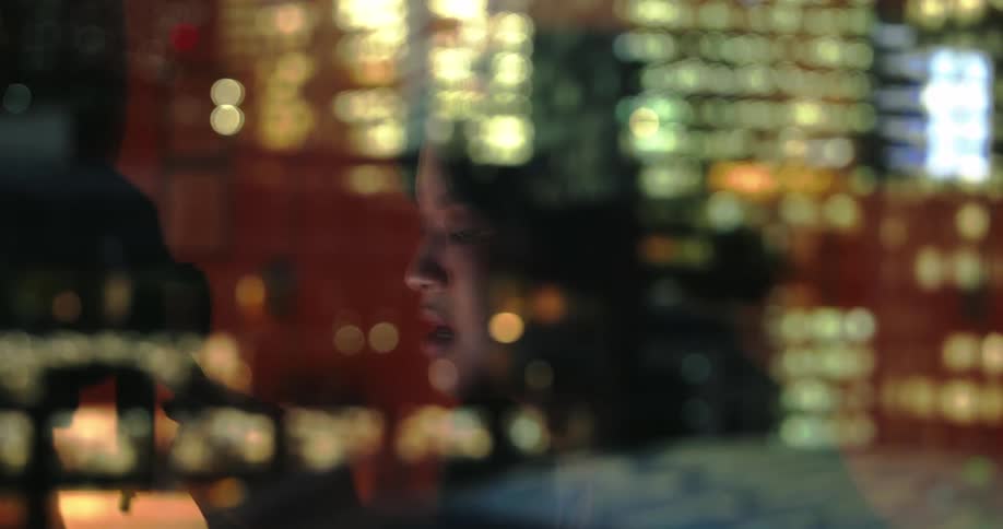 The woman is using a cell phone behind the window