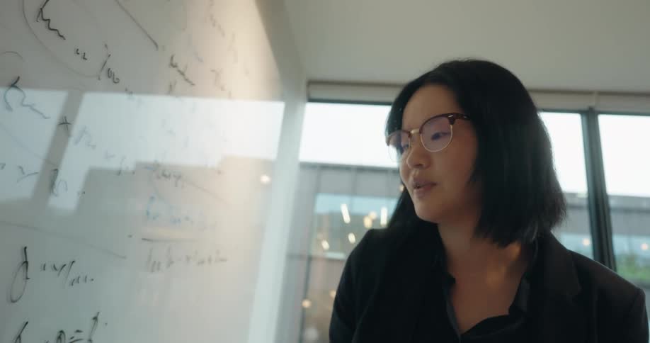 The woman talks and points to notes on the white board