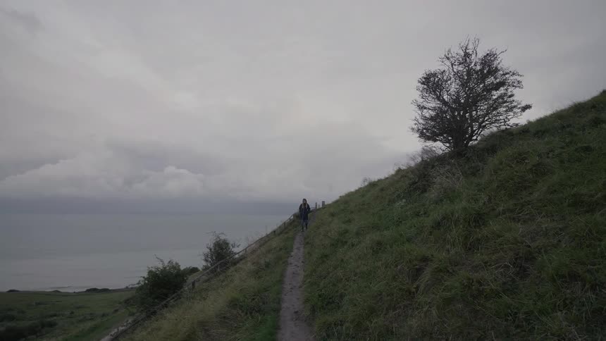 A man hikes down a dirt trail on a hill