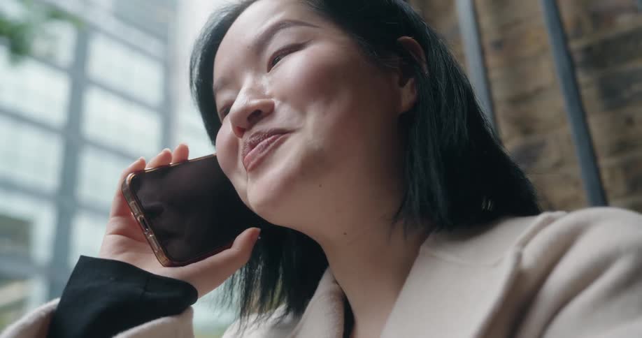 Woman smiles while talking on the phone near a window