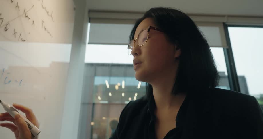 Woman writing notes on a transparent board during a meeting