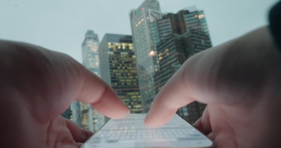 Female hands holding and texting on a smartphone in front of skyscrapers outdoors