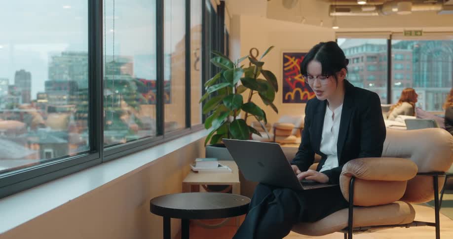 Woman works focused in modern coworking space with urban view and professional atmosphere
