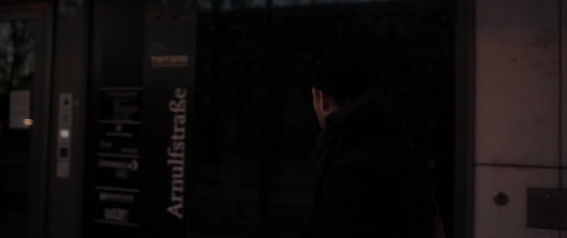 A man walks  on a city sidewalk at dusk
