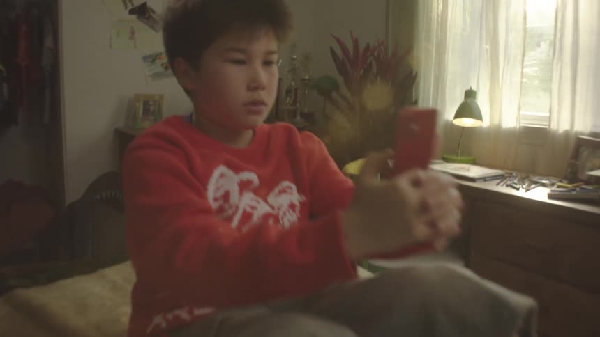 The boy sits up and texts on his phone