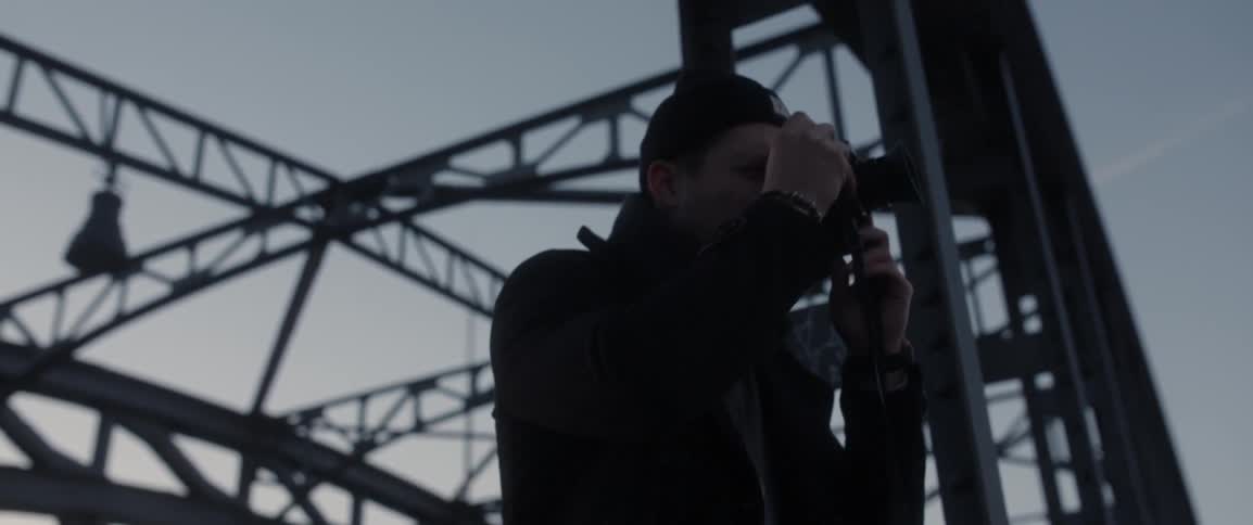A man wearing a black beanie takes pictures outside