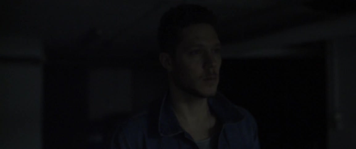 A man walks inside a dark room as the fluorescent light flickers on