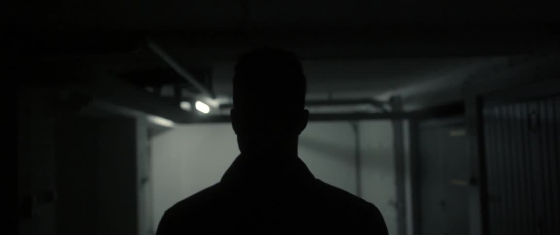 Man walks down a dimly lit hallway