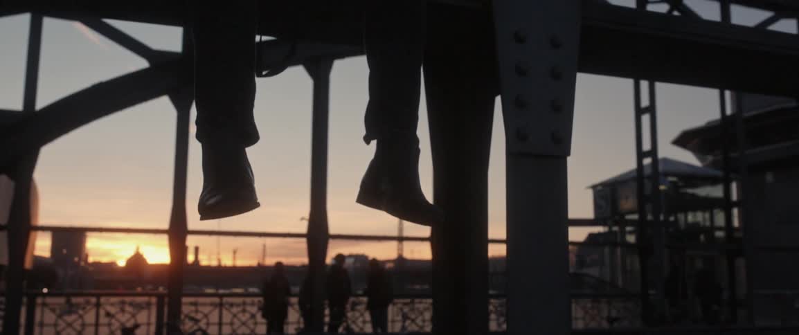 Person's legs dangle while sitting on a metal beam