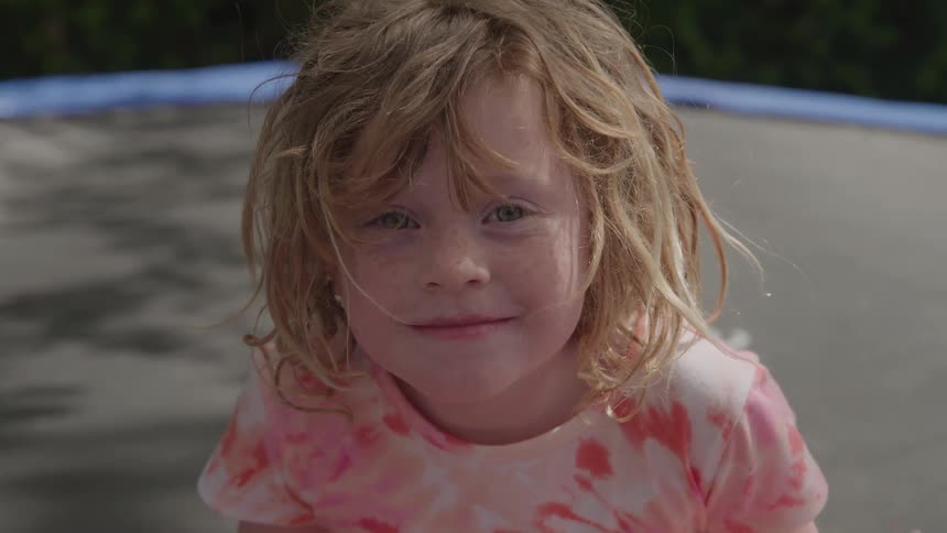 Child smiles with messy hair while playing outdoors
