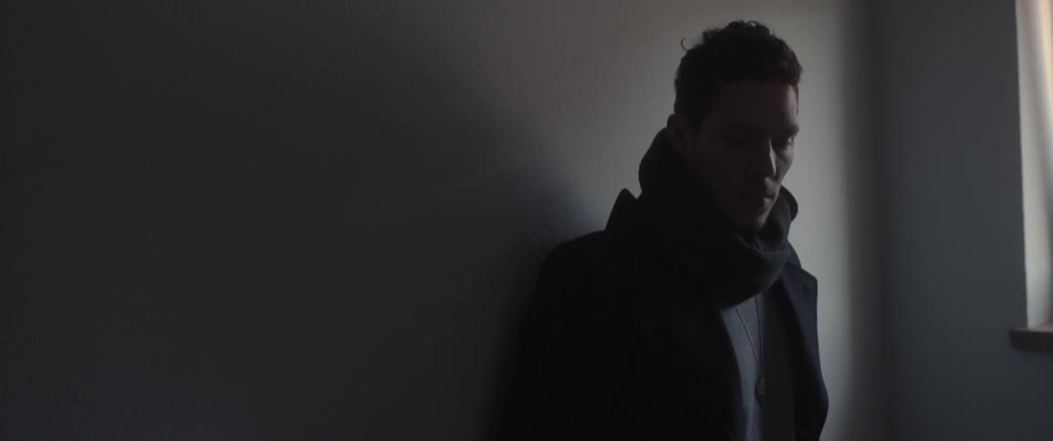 A man wearing a scarf looks toward some light
