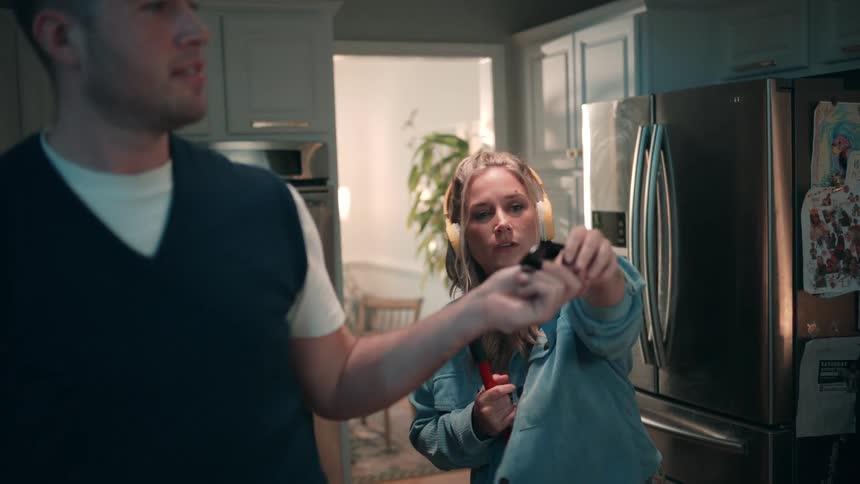 Man handing sunglasses to a woman who is cleaning the kitchen