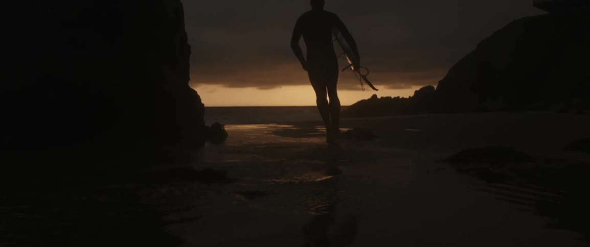 A man is carrying a surfboard running at dawn
