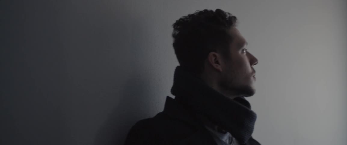 Man leaning against a wall and staring off