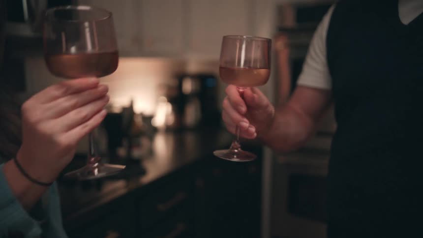 Glasses clink over a kitchen counter during a relaxed moment