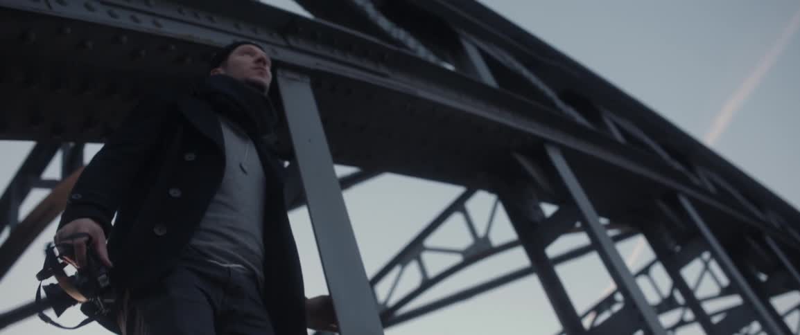 A man stands on the edge of a bridge with a camera