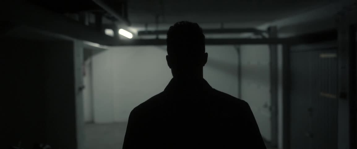 A man walks through a dim hallway