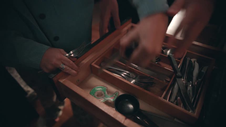 Hands organize cutlery inside a kitchen drawer