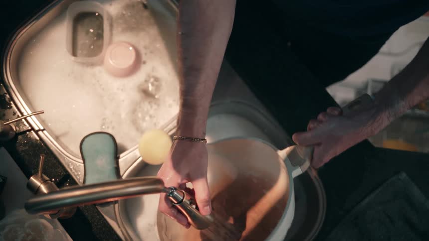 A person washing dishes in a sink